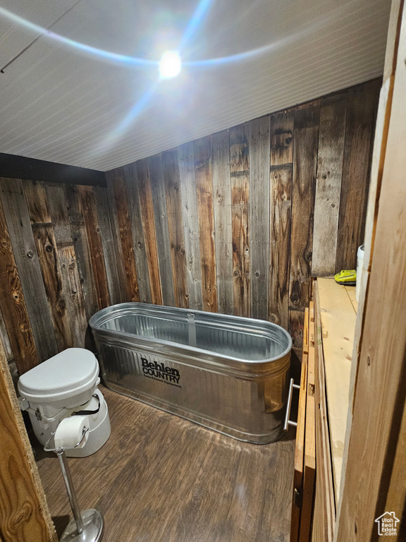 Bathroom with wood walls, vanity, wood-type flooring, and a bath