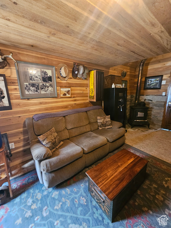 Living room with a wood stove, wooden walls, and wooden ceiling