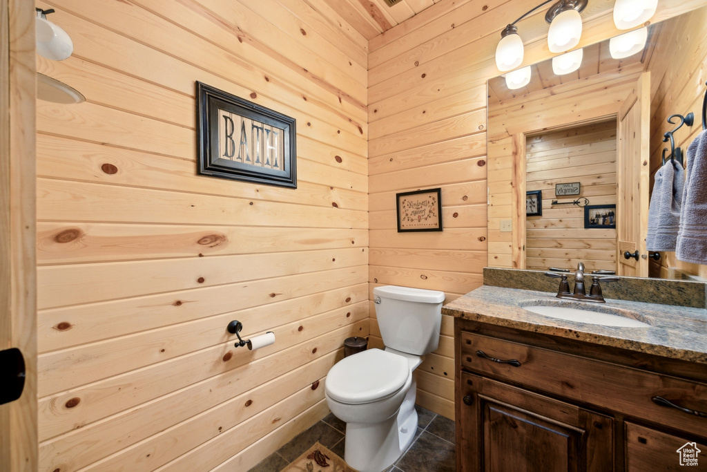 Bathroom featuring wooden walls, wood ceiling, toilet, tile patterned floors, and vanity