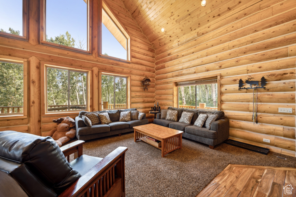 Living room featuring high vaulted ceiling, carpet floors, a healthy amount of sunlight, and log walls