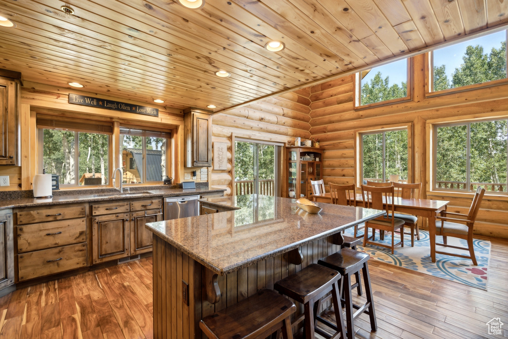 Kitchen featuring sink, dark stone countertops, hardwood / wood-style flooring, and rustic walls