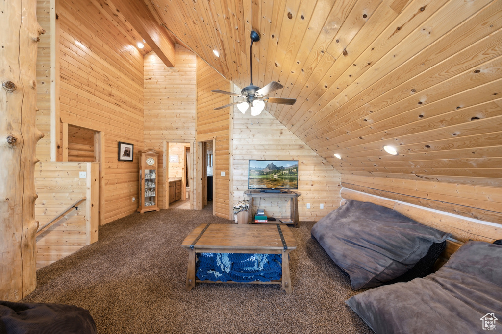 Carpeted living room featuring wooden walls, wooden ceiling, ceiling fan, and high vaulted ceiling