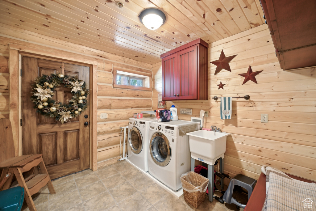 Washroom featuring cabinets, separate washer and dryer, wood walls, and light tile patterned floors