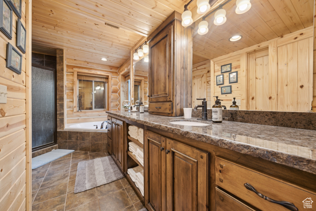 Bathroom featuring tile patterned flooring, wood walls, vanity, wooden ceiling, and separate shower and tub