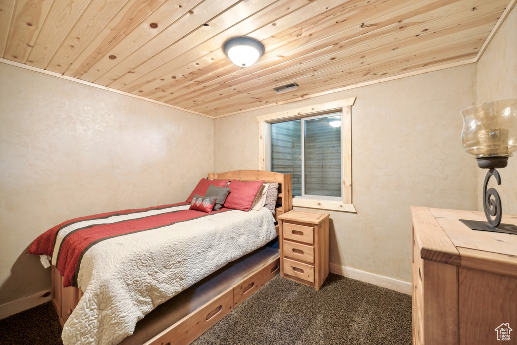 Bedroom with dark carpet, wooden ceiling, and crown molding