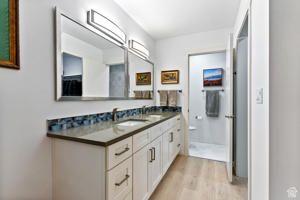 Bathroom featuring dual vanity, toilet, and hardwood / wood-style flooring