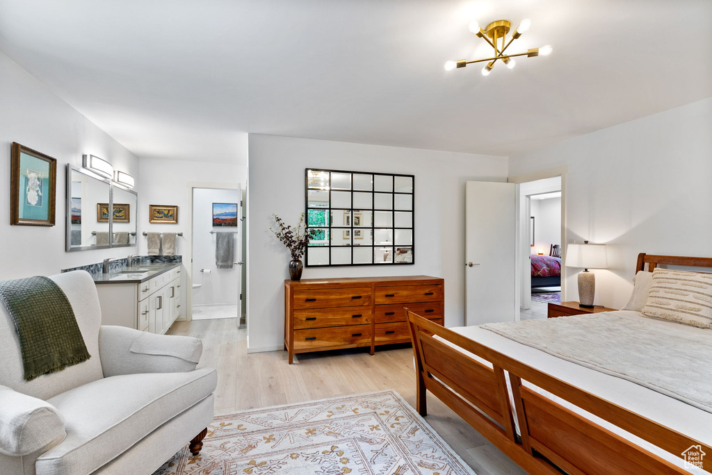 Bedroom with light hardwood / wood-style flooring, sink, ensuite bath, and an inviting chandelier