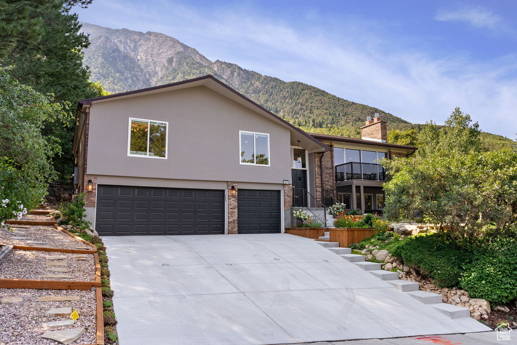 View of front of home featuring a garage, a balcony, and a mountain view