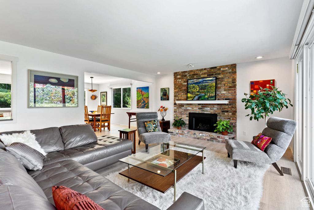 Living room featuring brick wall, light wood-type flooring, and a brick fireplace