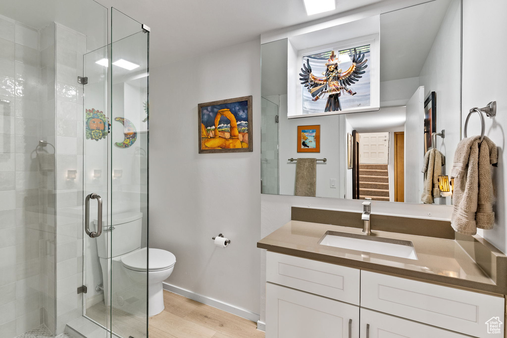 Bathroom with wood-type flooring, toilet, vanity, and an enclosed shower