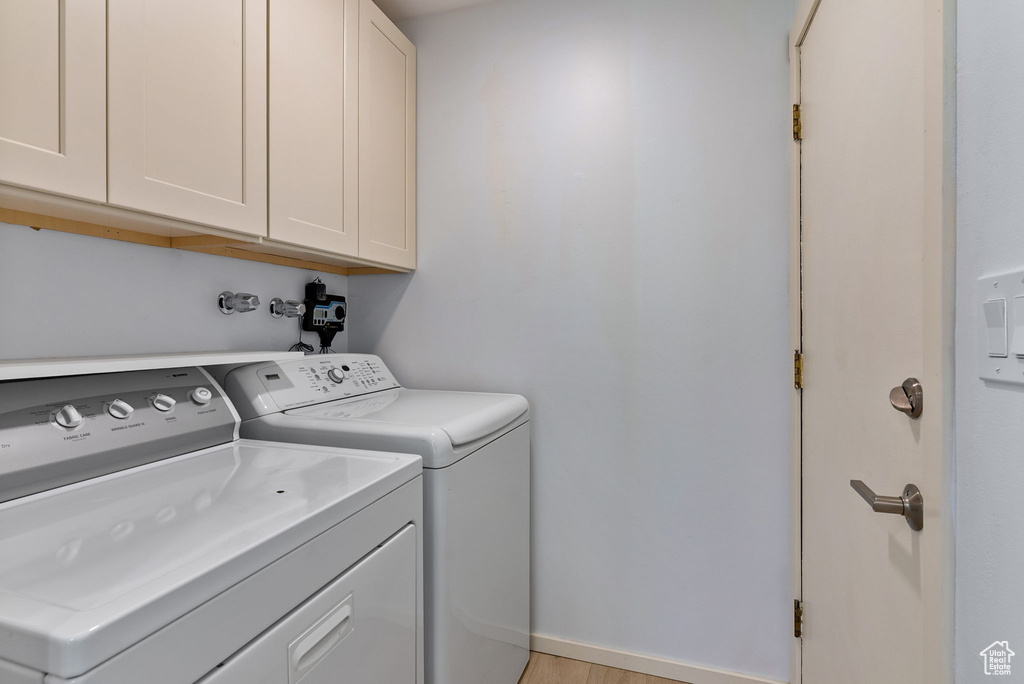 Laundry area with cabinets, washing machine and dryer, and light wood-type flooring