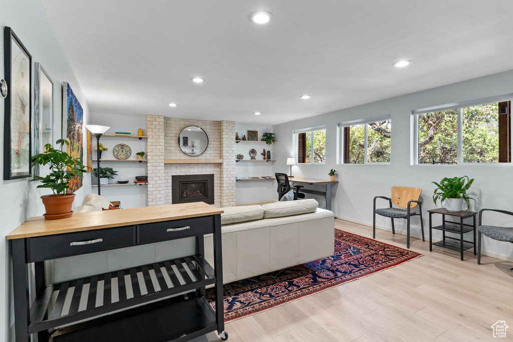 Living room with a fireplace, light hardwood / wood-style floors, and brick wall