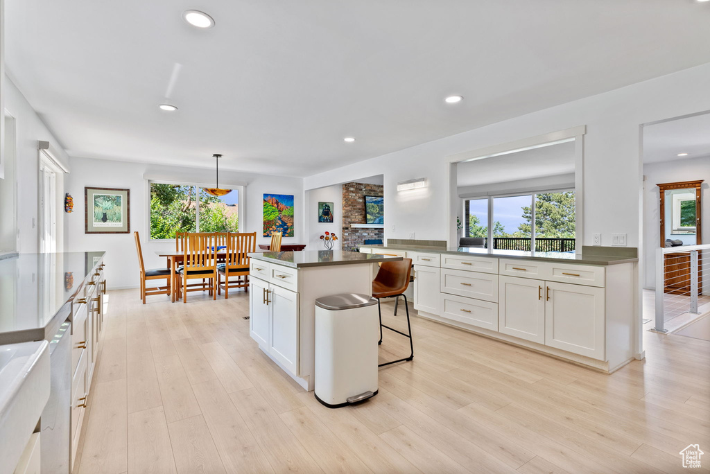 Kitchen featuring a kitchen bar, white cabinets, light hardwood / wood-style floors, and decorative light fixtures