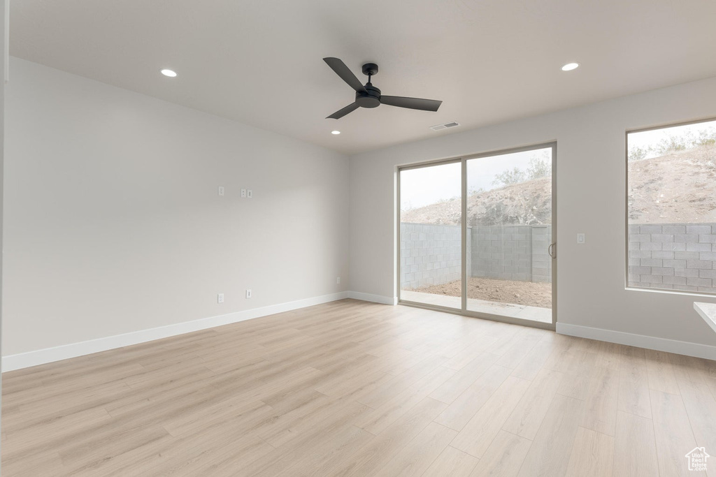 Empty room featuring ceiling fan, light hardwood / wood-style flooring, and a wealth of natural light