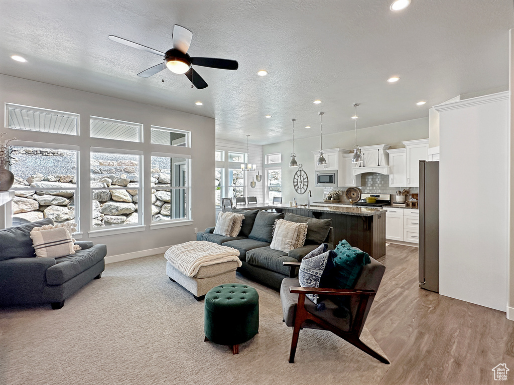 Living room with a textured ceiling, light hardwood / wood-style flooring, and ceiling fan