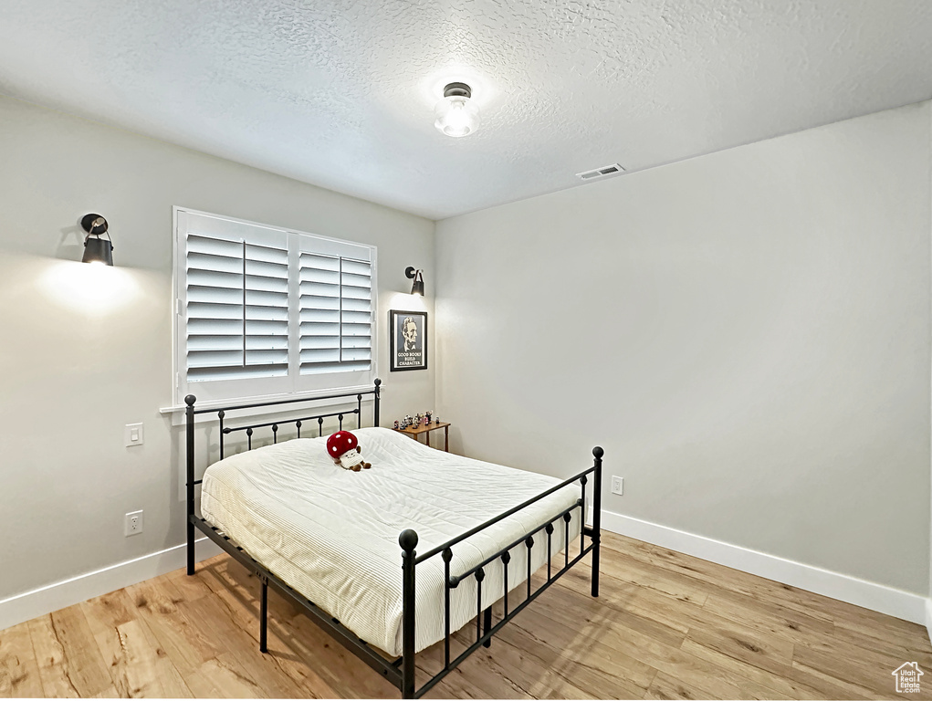 Bedroom with light hardwood / wood-style floors and a textured ceiling