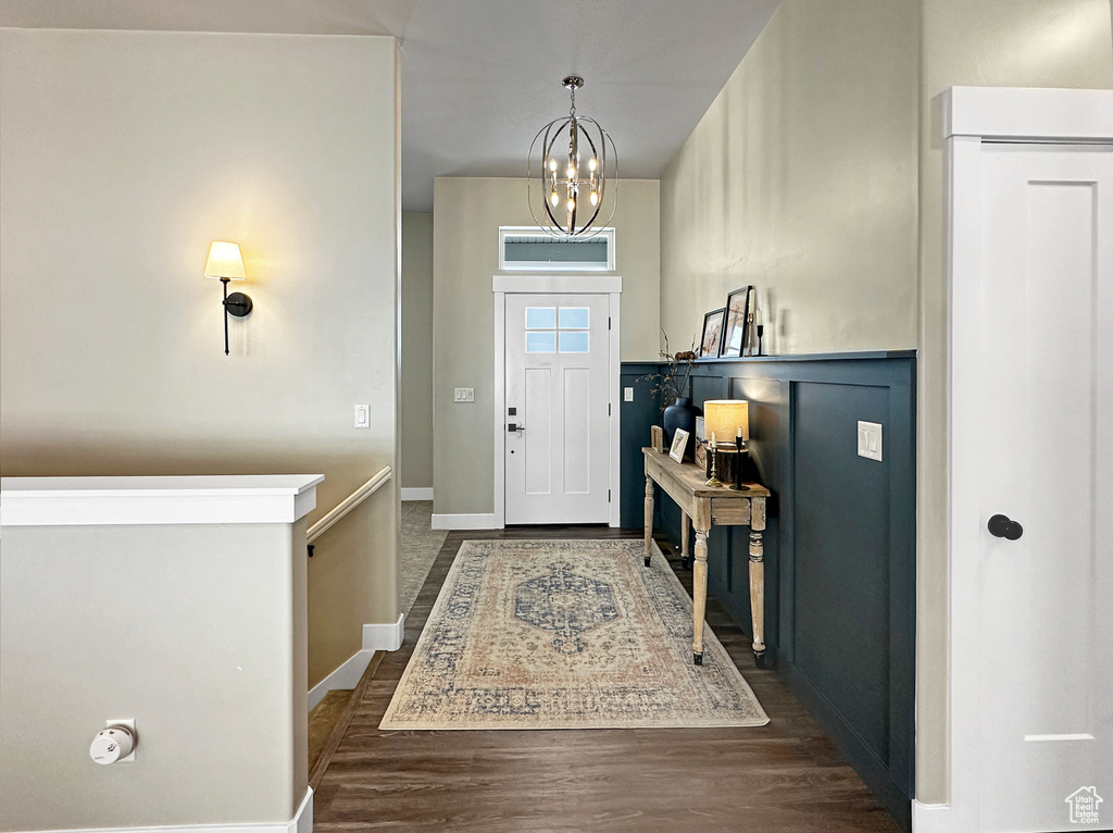 Entrance foyer with an inviting chandelier and dark hardwood / wood-style flooring