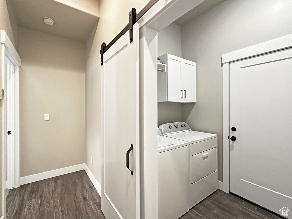 Laundry area with separate washer and dryer, cabinets, a barn door, and dark hardwood / wood-style floors