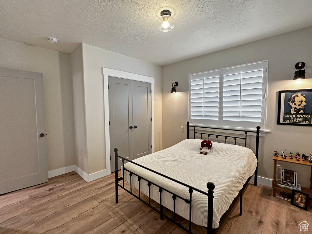 Bedroom with a textured ceiling, a closet, and wood-type flooring