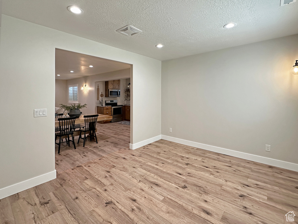 Empty room featuring light hardwood / wood-style floors and a textured ceiling