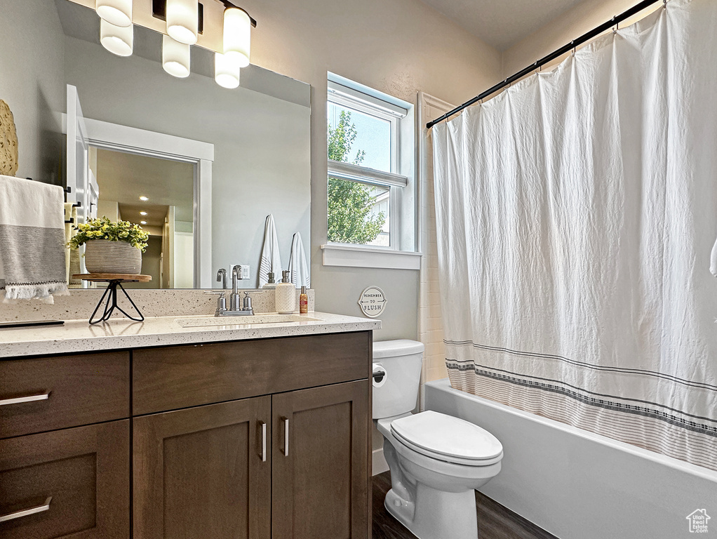 Full bathroom with vanity, shower / tub combo, hardwood / wood-style flooring, and toilet