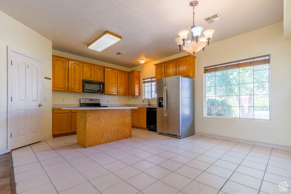 Kitchen with a chandelier, black appliances, light tile patterned floors, and a kitchen island