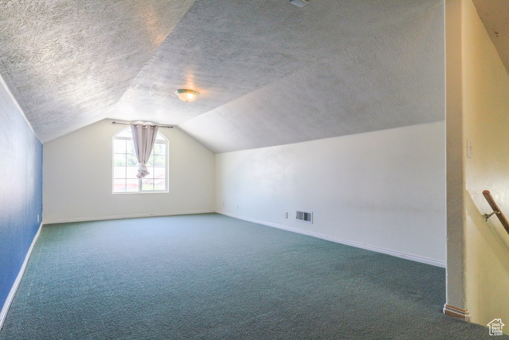 Bonus room with lofted ceiling, carpet floors, and a textured ceiling