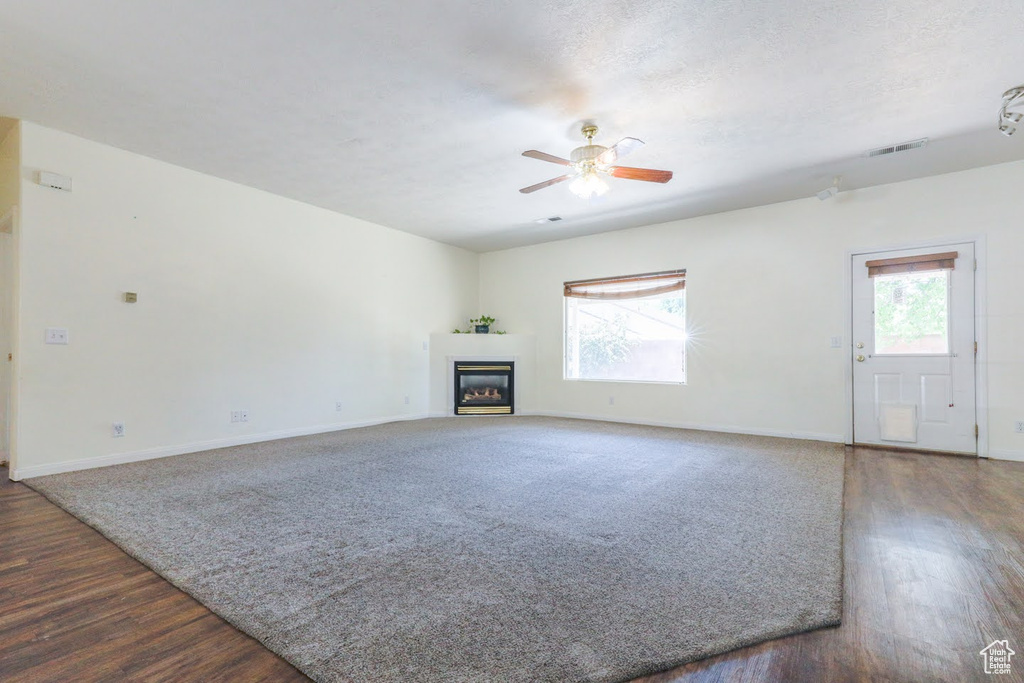 Unfurnished living room with dark hardwood / wood-style floors and ceiling fan