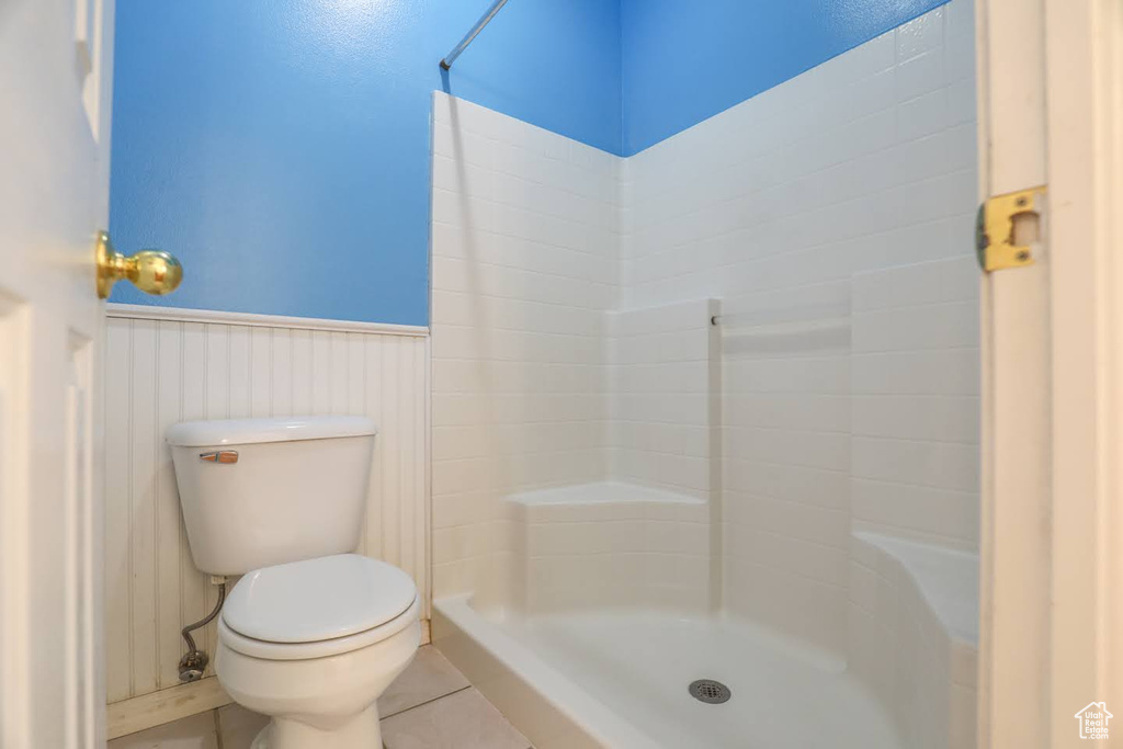 Bathroom with toilet, tile patterned floors, and a shower