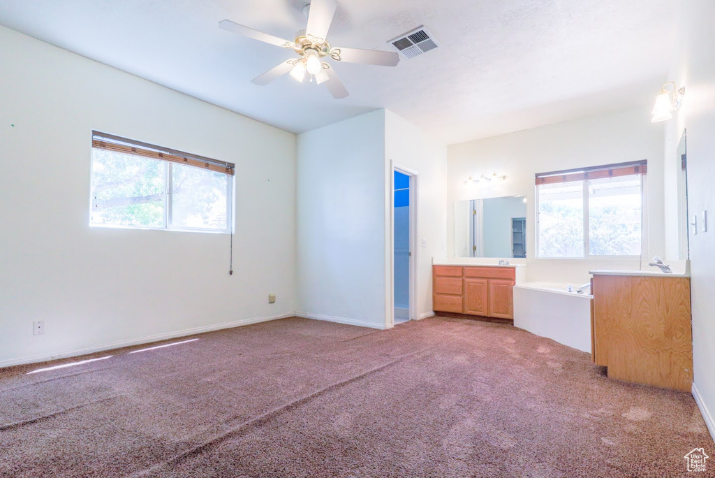 Unfurnished bedroom featuring multiple windows, carpet, and ceiling fan