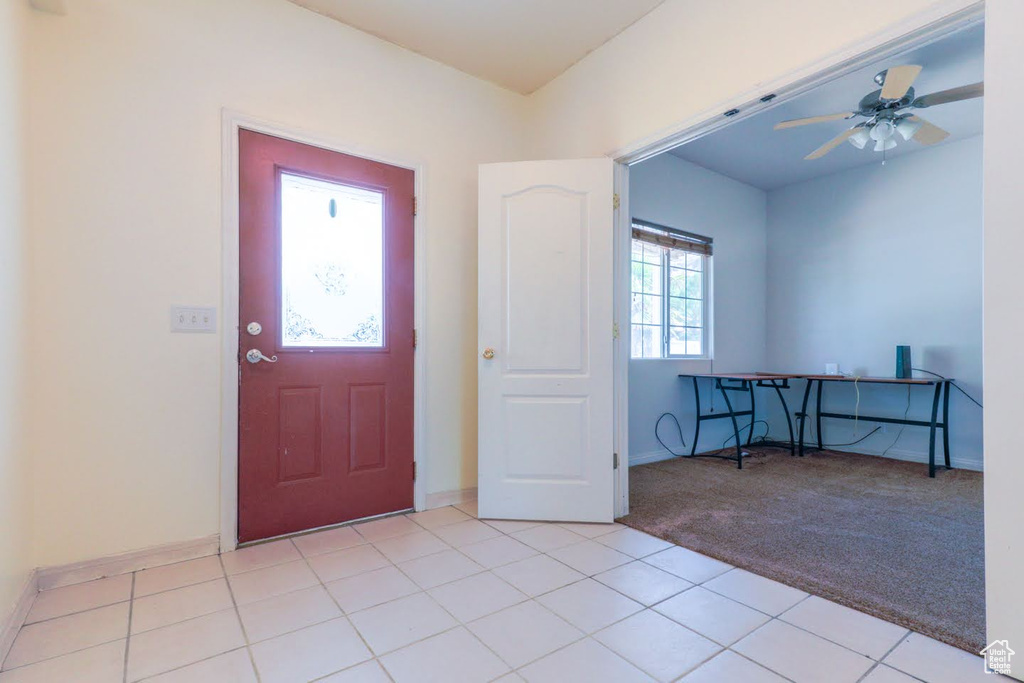 Entryway with light tile patterned floors and ceiling fan