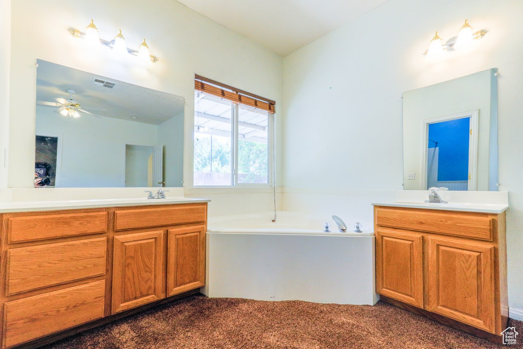 Bathroom with vanity, ceiling fan, and a bath