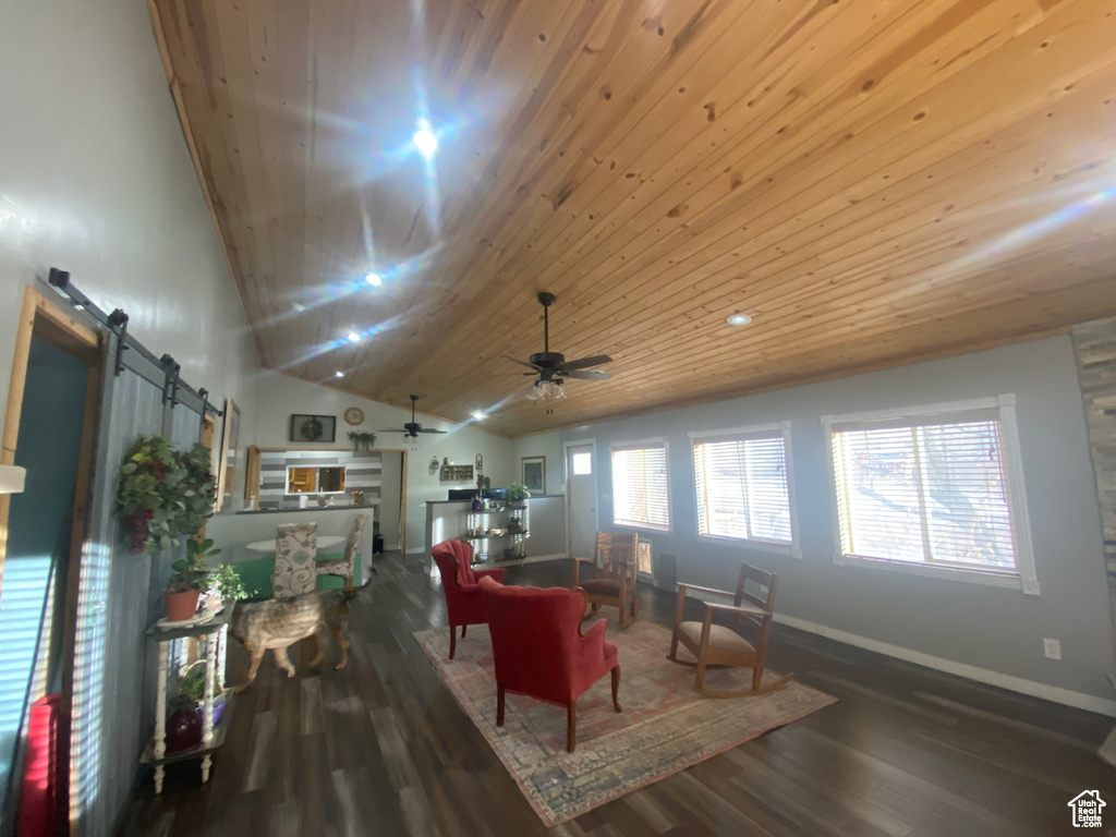 Living room featuring hardwood / wood-style floors, vaulted ceiling, a barn door, wooden ceiling, and ceiling fan