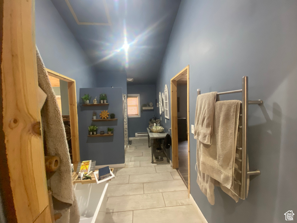 Bathroom featuring a baseboard heating unit, lofted ceiling, and tile patterned floors