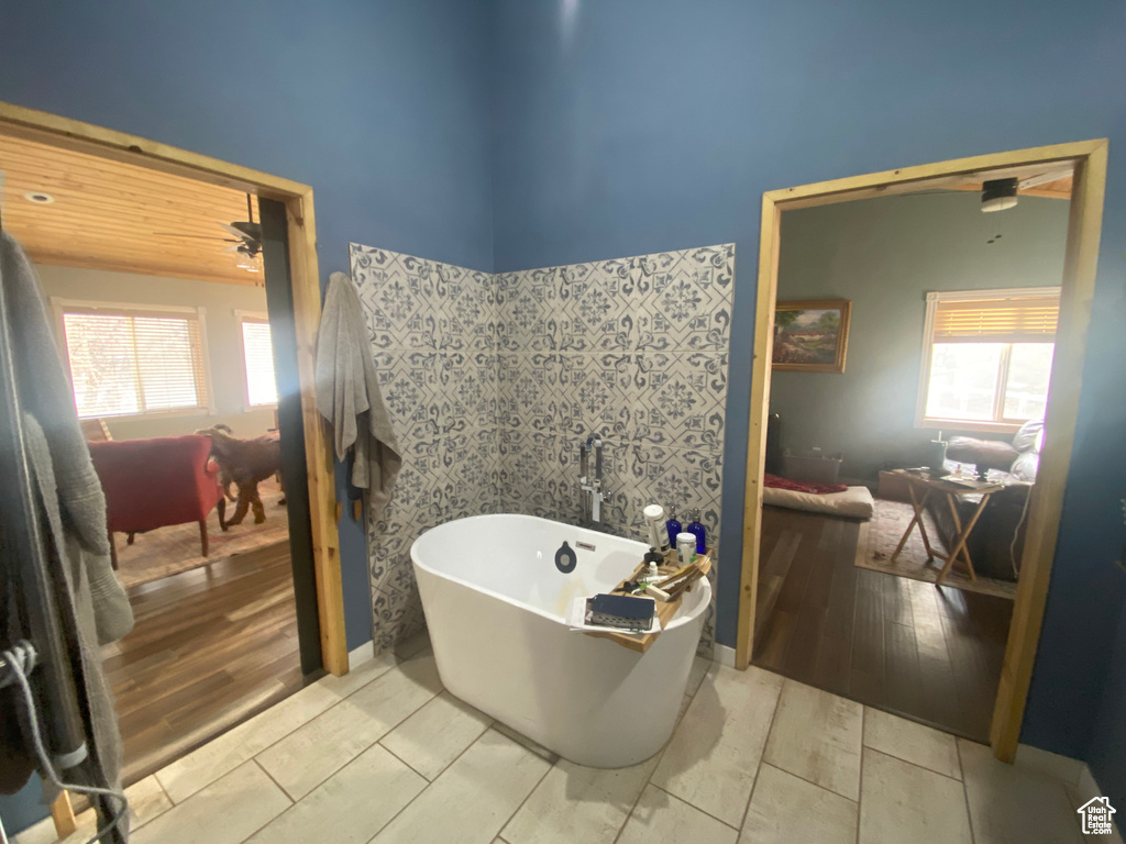 Bathroom featuring hardwood / wood-style flooring, a tub to relax in, a wealth of natural light, and ceiling fan