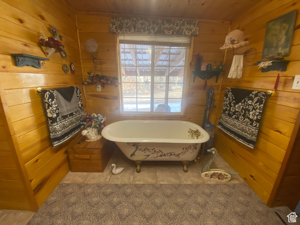 Bathroom featuring a bath, wooden walls, and wooden ceiling