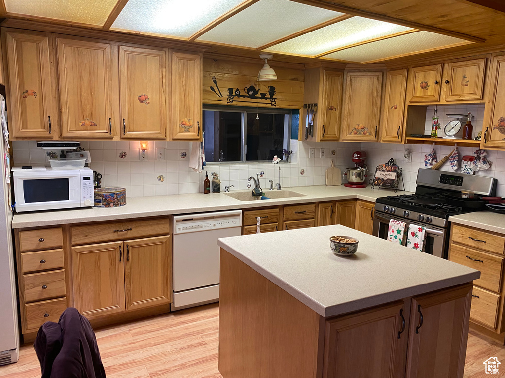 Kitchen featuring a center island, light wood-type flooring, white appliances, and sink