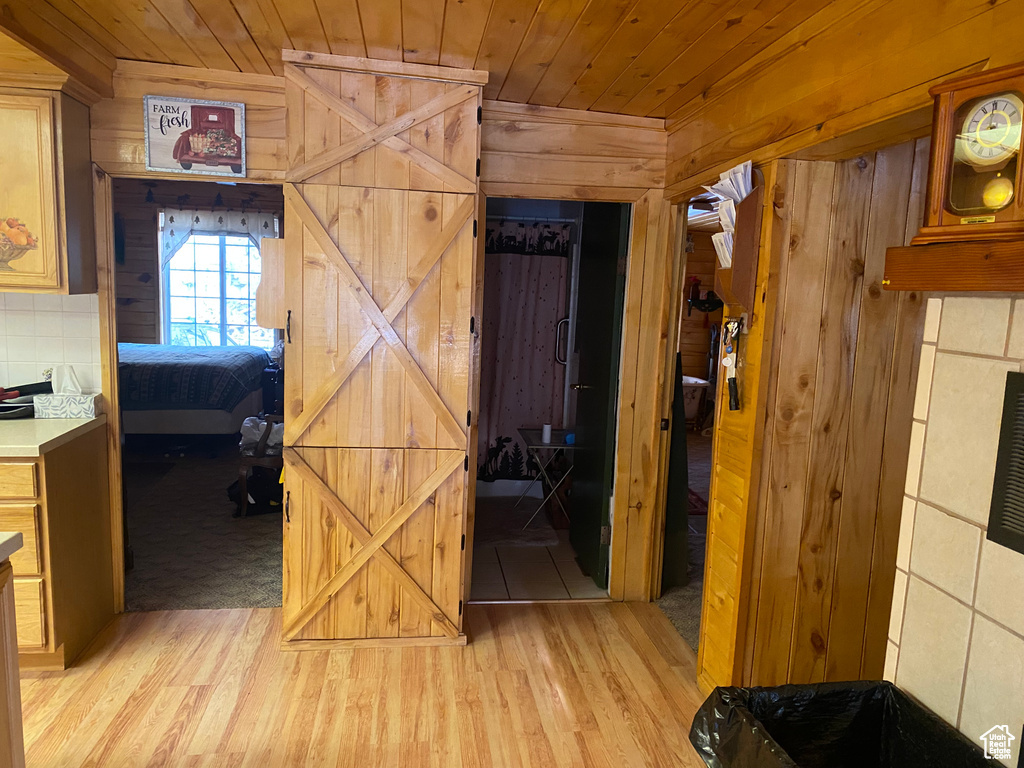 Hall with wood ceiling, wooden walls, and light hardwood / wood-style flooring