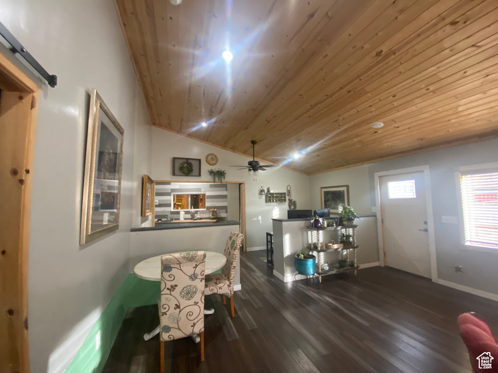 Dining area featuring lofted ceiling, a barn door, ceiling fan, hardwood / wood-style floors, and wooden ceiling