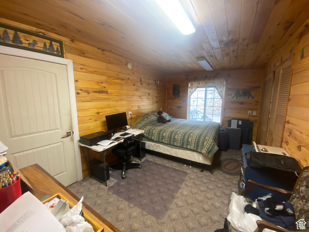 Bedroom featuring carpet flooring, wooden walls, and wood ceiling