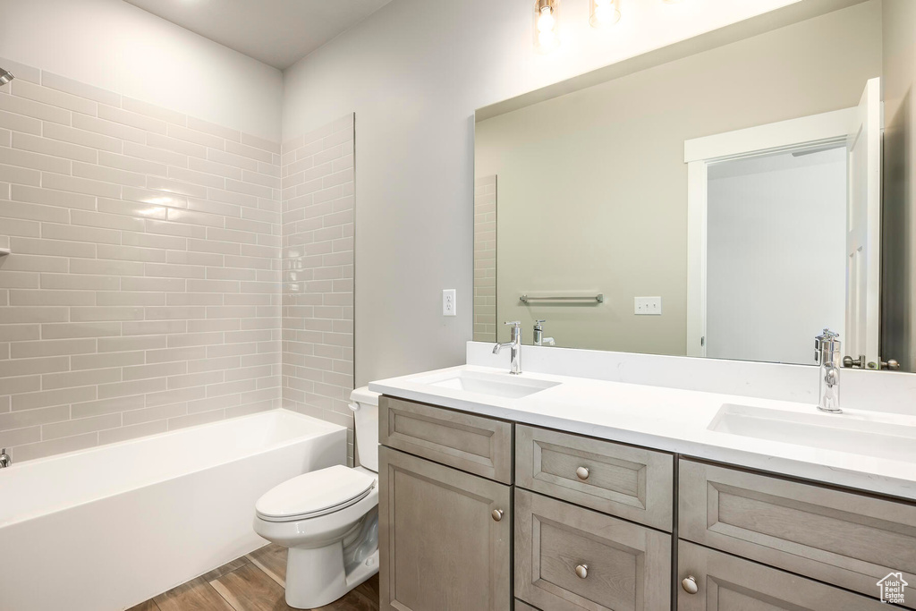 Full bathroom featuring toilet, tiled shower / bath, hardwood / wood-style flooring, and double sink vanity