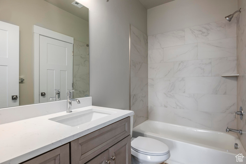 Full bathroom featuring tiled shower / bath combo, vanity, and toilet