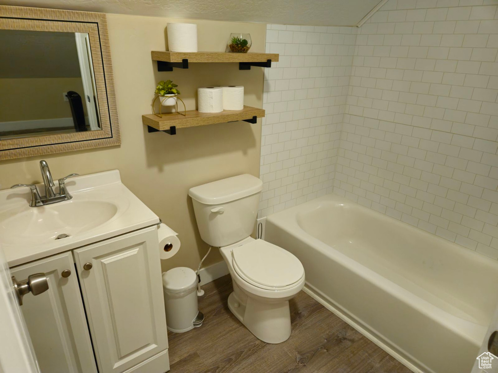 Full bathroom with wood-type flooring, toilet, vanity, and tiled shower / bath combo