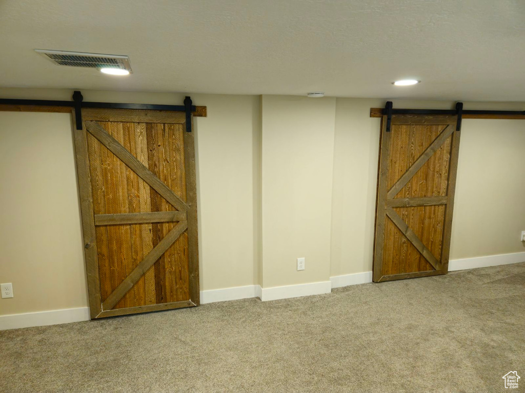 Basement featuring a barn door and carpet