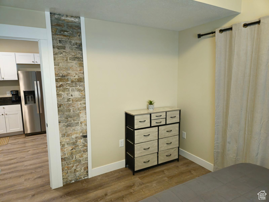 Bedroom with wood-type flooring, a barn door, and stainless steel refrigerator with ice dispenser