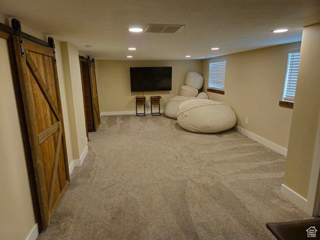 Living area with a barn door and light colored carpet