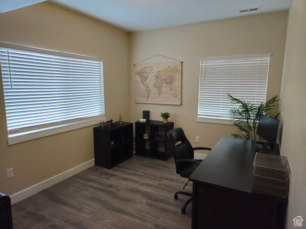 Home office with dark wood-type flooring and a healthy amount of sunlight