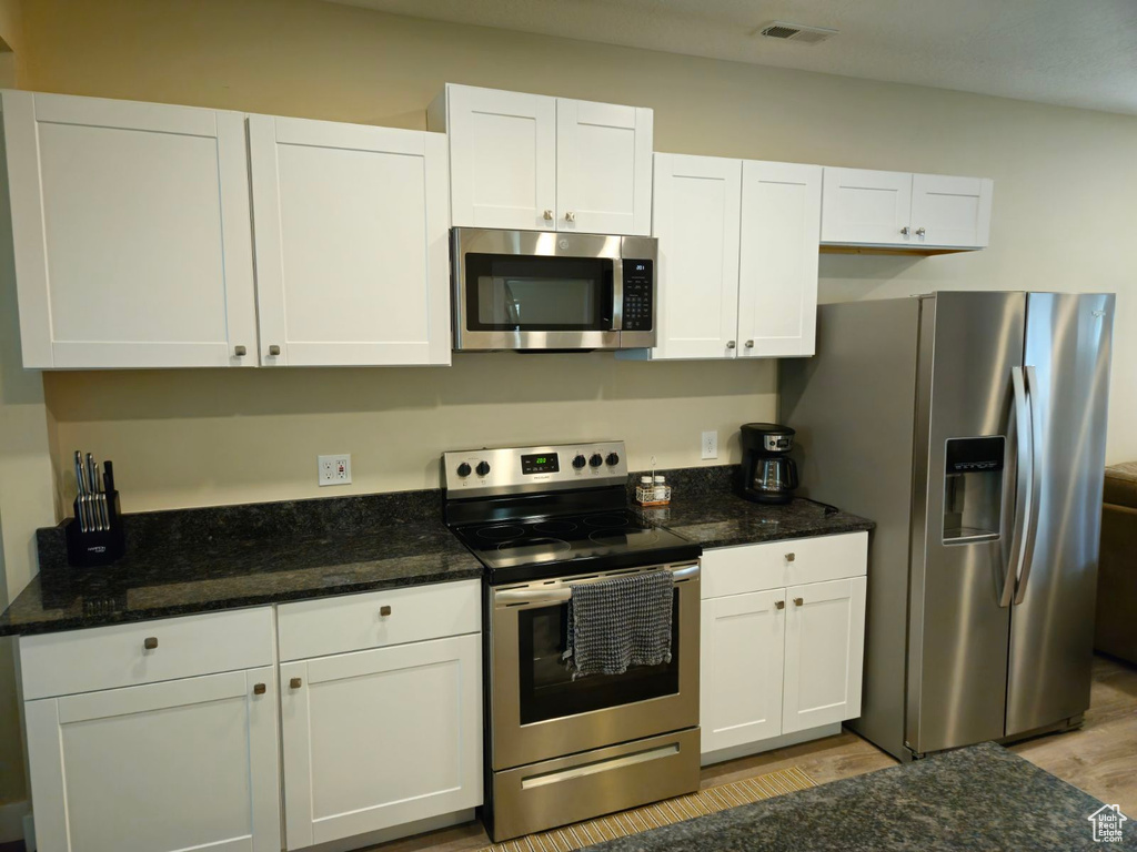 Kitchen with light hardwood / wood-style flooring, white cabinetry, and stainless steel appliances