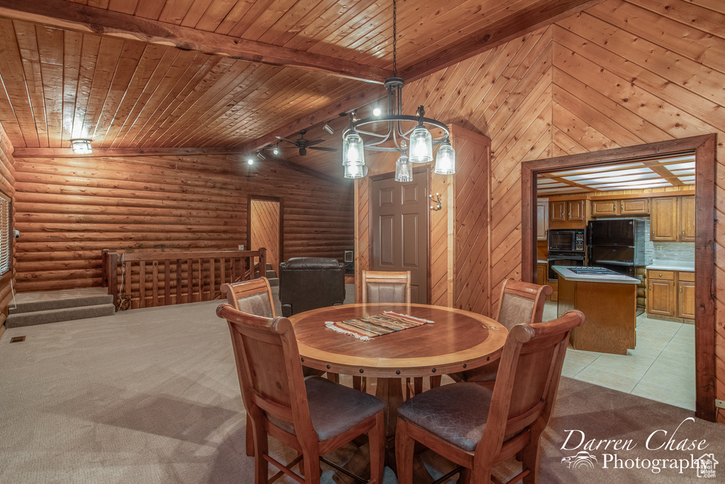 Carpeted dining area with vaulted ceiling with beams, rail lighting, rustic walls, ceiling fan, and wooden ceiling