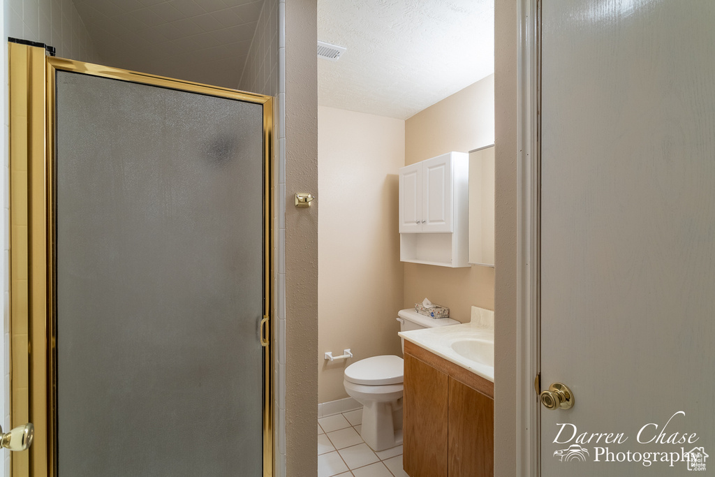 Bathroom with a shower with door, vanity, toilet, and tile patterned floors